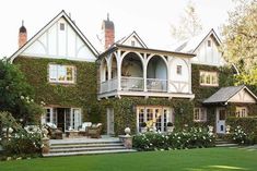 a large house covered in vines and flowers with stairs leading up to the front door