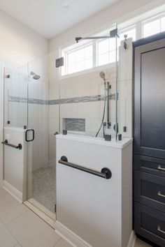 a bathroom with a walk in shower sitting next to a sink and drawers on the wall