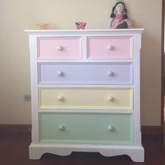 a white dresser with multicolored drawers and a stuffed animal on top of it