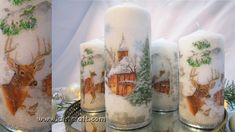 three candles decorated with images of deer and houses in the snow, one is lit