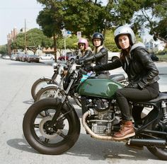 three women are riding motorcycles down the street