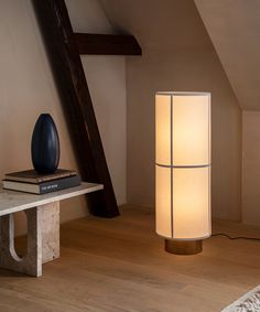 a lamp that is on top of a table next to a book and some books