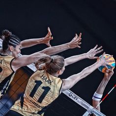 three female volleyball players reaching for the ball