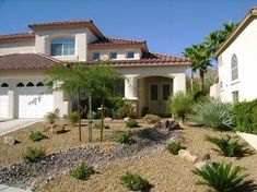 a large white house with palm trees in the front yard and landscaping on the side