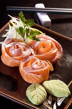 some food is on a black plate with chopsticks