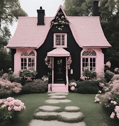 a pink and black house surrounded by flowers