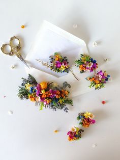 flowers and scissors are laying on the ground next to a piece of paper that has been cut in half