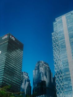 some very tall buildings in the city with blue sky behind them on a sunny day