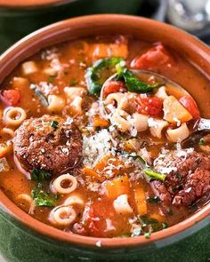 a bowl of soup with meatballs, pasta and spinach on the side in it