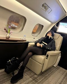 a woman is sitting in an airplane with her feet up on the seat and wearing black boots