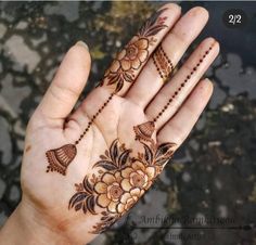 a woman's hand with henna tattoos on it and flowers painted on the palm