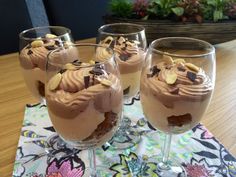 three glasses filled with dessert sitting on top of a table