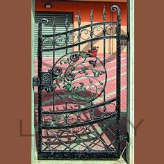 a wrought iron gate in front of an orange house with pink walls and flooring