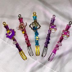 six different colored keychains with hello kitty charms on them sitting on a white sheet