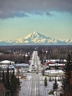 an empty street with snow covered mountains in the background