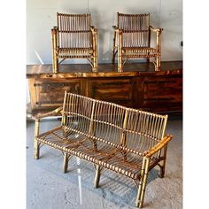 three bamboo chairs sitting next to each other in front of a dresser with drawers on it