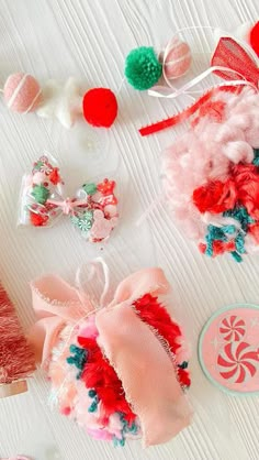 several hair accessories are laid out on a white tablecloth with red, pink and green pom poms