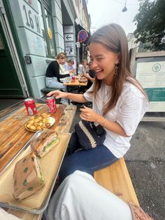 a woman sitting at a table with food in front of her and another person behind her