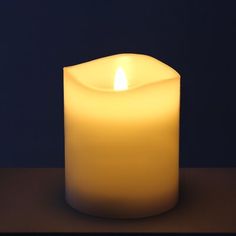 a lit candle sitting on top of a table next to a black wall with a blue background