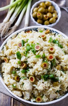 a bowl filled with rice and olives on top of a wooden table