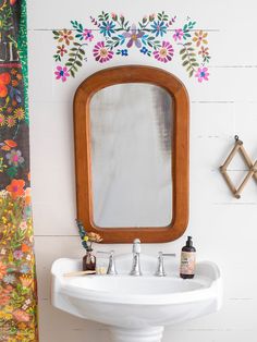 a white sink sitting under a wooden mirror