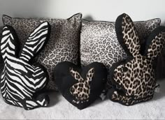 three stuffed animals sitting next to each other on top of a bed covered in animal print pillows