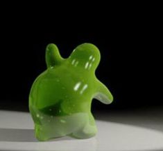 a green toy turtle sitting on top of a white table next to a black background