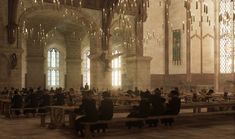 people sitting at tables in a large building with chandeliers hanging from the ceiling