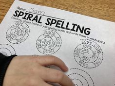 a hand on top of a piece of paper that says spiral spelling