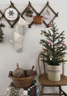 a small christmas tree in a basket next to a wooden chair and wall hangings