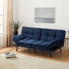 a blue couch sitting on top of a hard wood floor next to a white rug