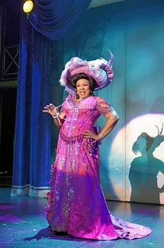 a woman in a pink dress and hat on stage