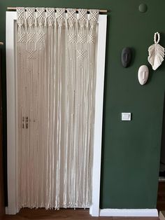 a white curtain hanging on the side of a green wall next to a wooden door