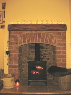 a fireplace with a fire burning in it and some lights on the mantel above