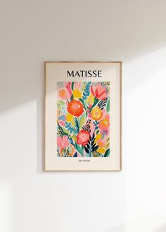 a painting hanging on the wall next to a vase with flowers and leaves in it