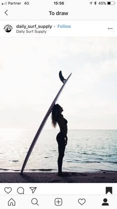 a woman standing on the beach holding a surfboard