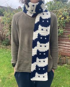 a woman wearing a knitted scarf with cats on it in blue, white and black