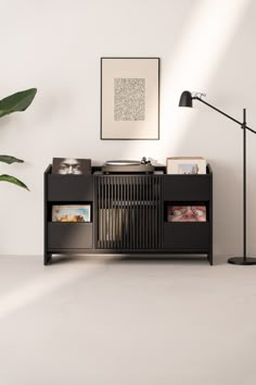 a record player sitting on top of a wooden cabinet next to a lamp and potted plant