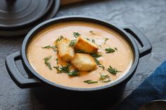 a bowl of soup with croutons in it on a table next to spoons