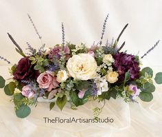 an arrangement of flowers and greenery on a white tablecloth with the words, the floral artisan studio