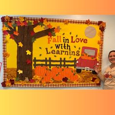 a woman standing in front of a bulletin board with fall leaves and pumpkins on it