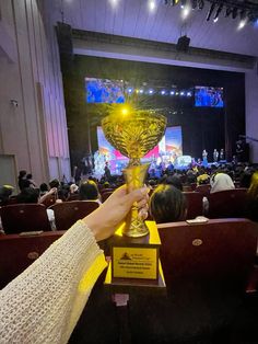 a person holding up a trophy in front of an audience at a convention or competition