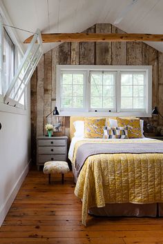 a bedroom with wood floors and white walls has a yellow quilt on it's bed