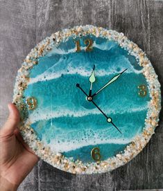 a hand holding a clock that is made to look like an ocean wave with gold numbers