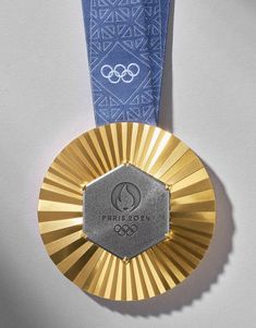 a gold medal with a blue ribbon hanging from it's side on a white surface