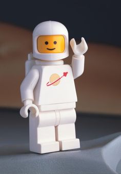 a lego spaceman is holding his hand up