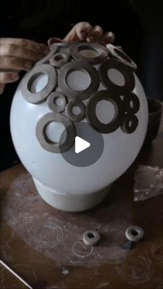 a white vase sitting on top of a table covered in circles and holes that look like rings