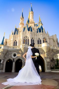 a bride and groom standing in front of the castle at disney's magic kingdom