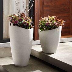 two white planters sitting on top of a window sill next to a door