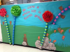 a bulletin board decorated with paper flowers and pom poms in the shape of trees